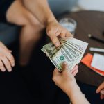 Aperçu rapproché de mains échangeant des billets en dollars à l'intérieur, symbolisant le paiement.