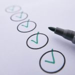 Close-up of a checklist with green checkmarks on white paper using a marker. Gros plan d'une liste de contrôle avec des coches vertes sur du papier blanc à l'aide d'un marqueur.