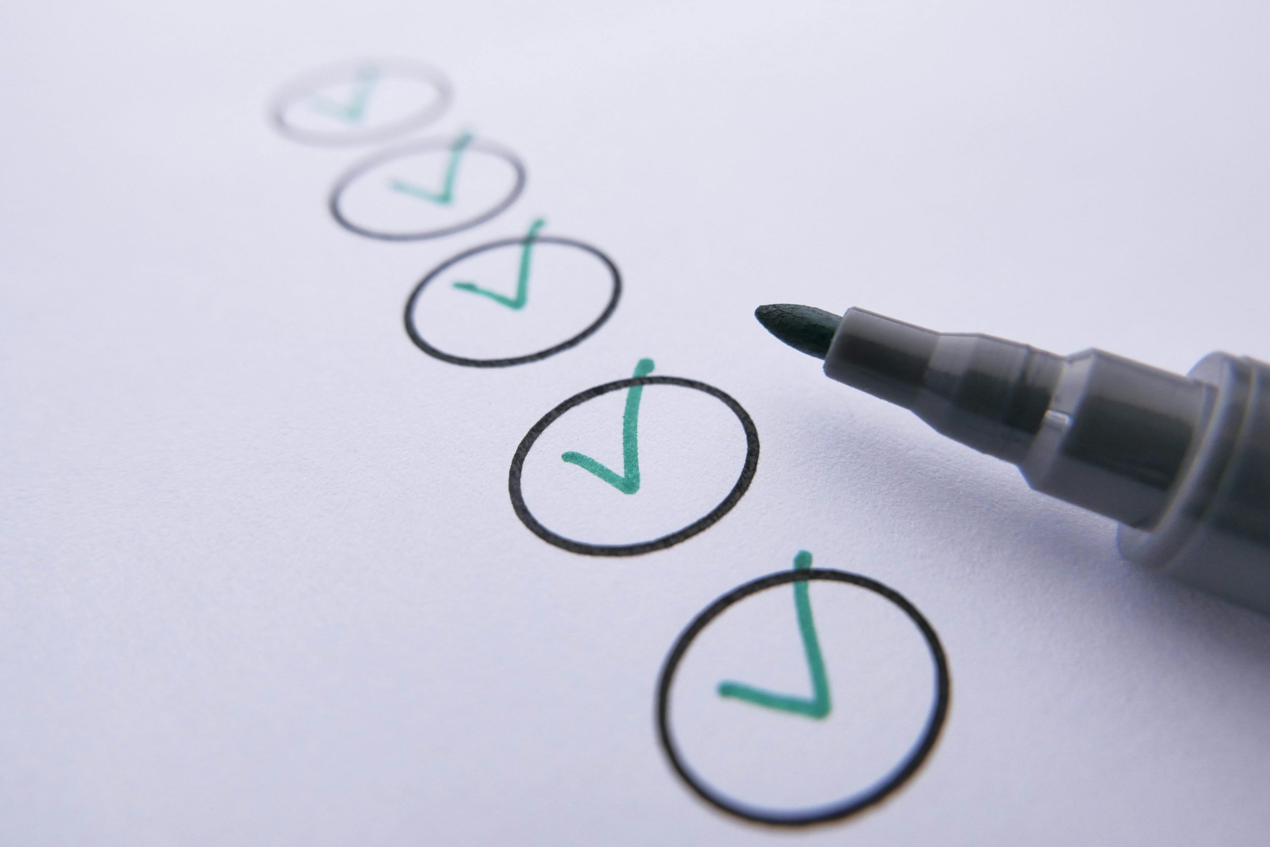 Close-up of a checklist with green checkmarks on white paper using a marker. Gros plan d'une liste de contrôle avec des coches vertes sur du papier blanc à l'aide d'un marqueur.