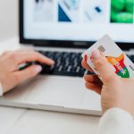 Close-up of hands using a laptop and holding a credit card for an online transaction. Gros plan sur les mains utilisant un ordinateur portable et tenant une carte de crédit pour une transaction en ligne.