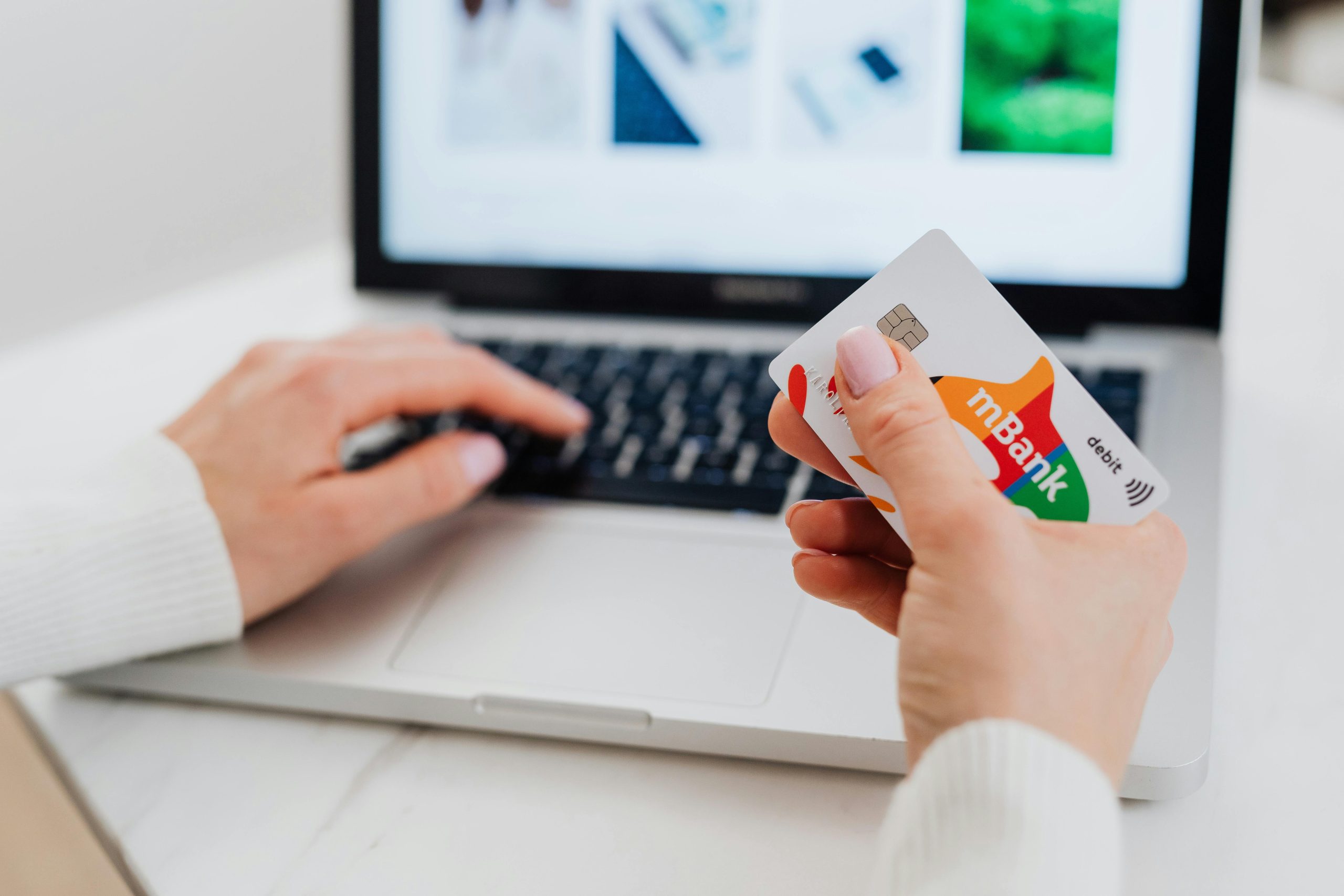 Close-up of hands using a laptop and holding a credit card for an online transaction. Gros plan sur les mains utilisant un ordinateur portable et tenant une carte de crédit pour une transaction en ligne.