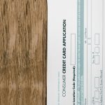 Close-up of a consumer credit card application form on a wooden surface, indicating financial paperwork. Gros plan sur un formulaire de demande de carte de crédit à la consommation sur une surface en bois, indiquant des documents financiers.