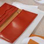 A close-up view of a handcrafted red leather card holder, showcasing craftsmanship. Une vue rapprochée d'un porte-cartes en cuir rouge fait à la main, mettant en avant l'artisanat.