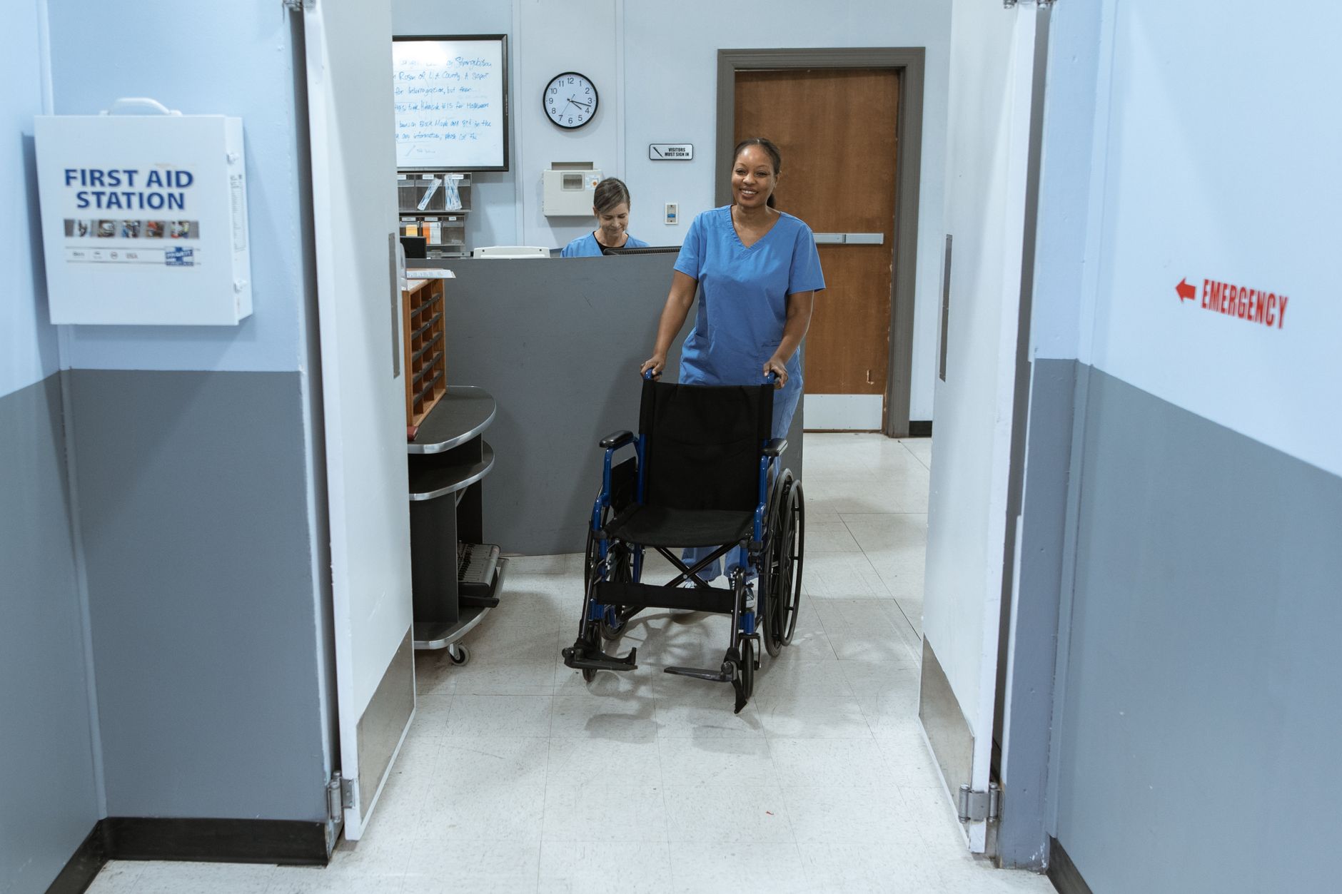 Soignante poussant un fauteuil roulant vide