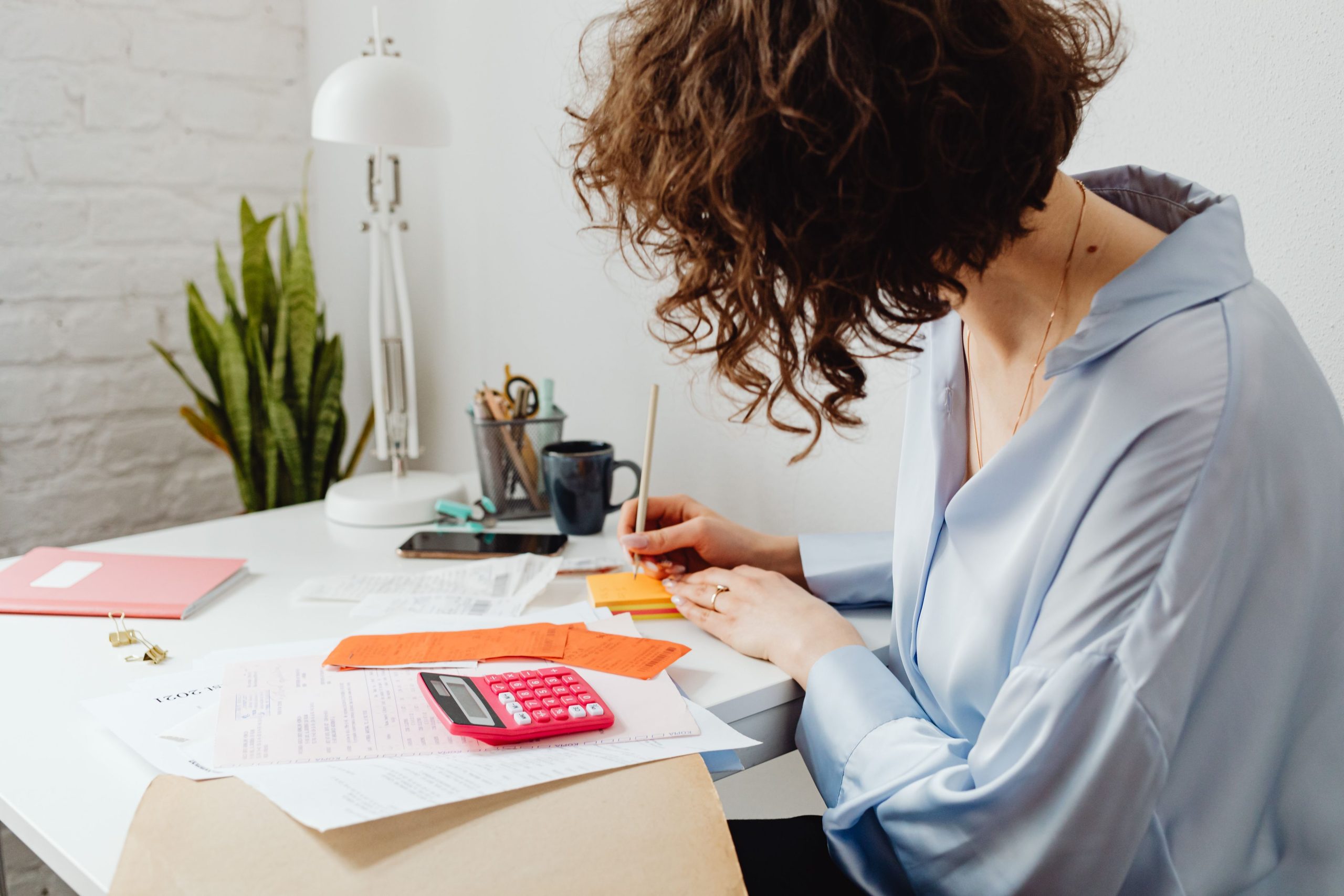 Une gestionnaire note ses calculs à côté d’une calculatrice
