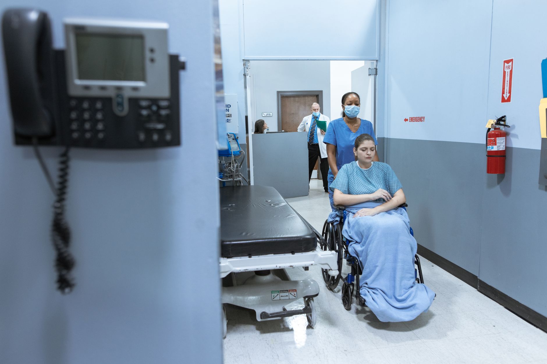 Soignante accompagnant un patient en fauteuil roulant