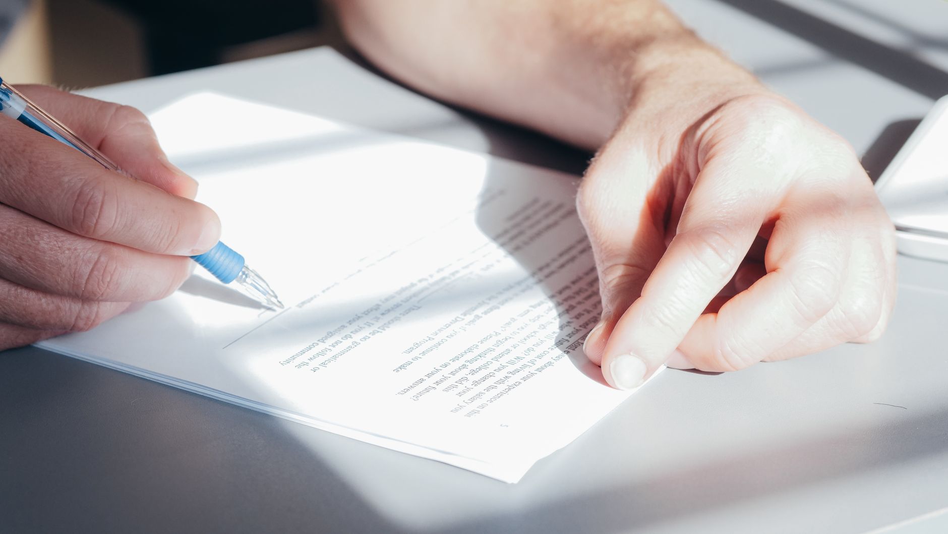 Mains qui signent un contrat avec un stylo bleu